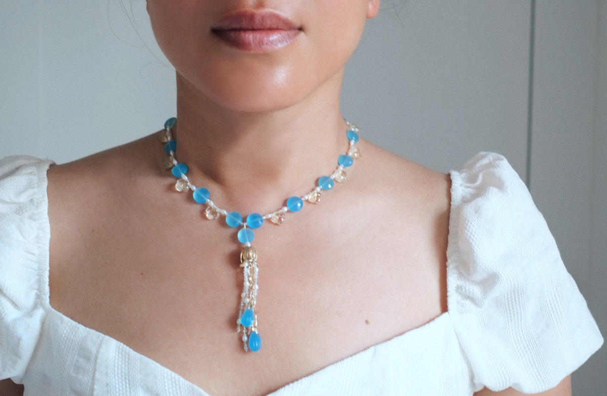 Crop of woman wearing blue necklace