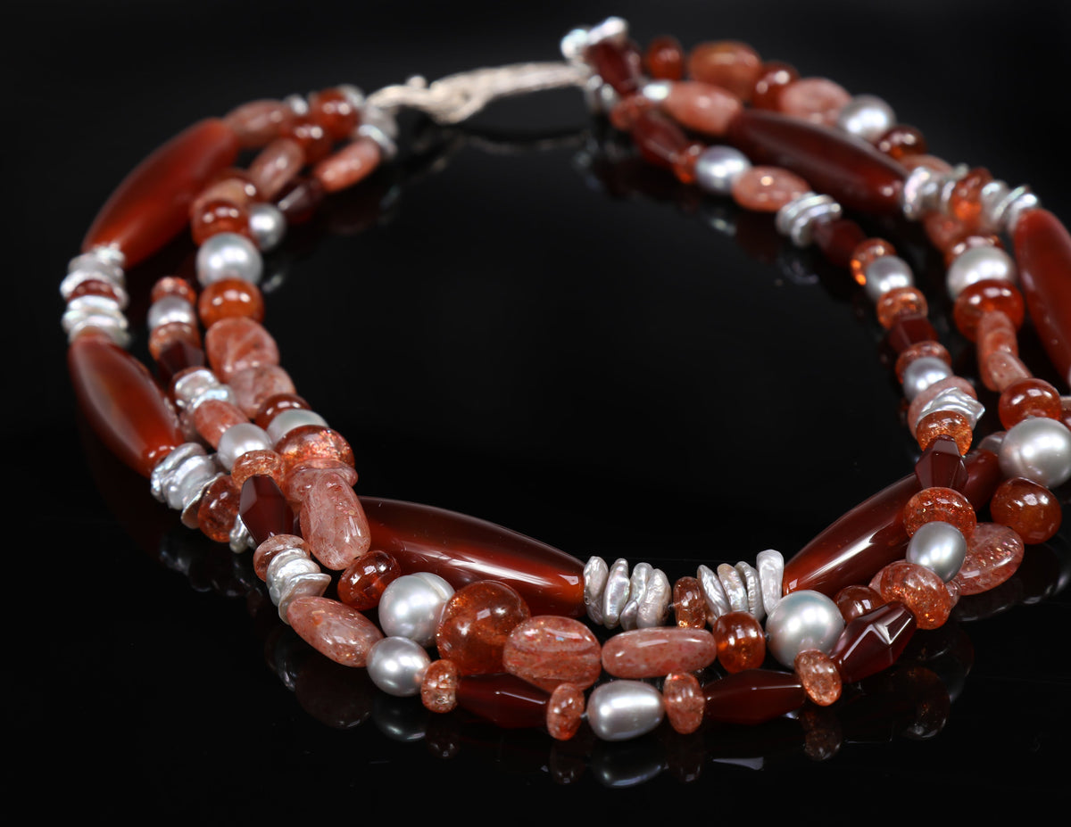 Sterling silver.  Gems:  carnelian, sunstone, and silver freshwater pearls.  White Orchid Studio’s vanilla bean clasp.  Approximate length:  18”